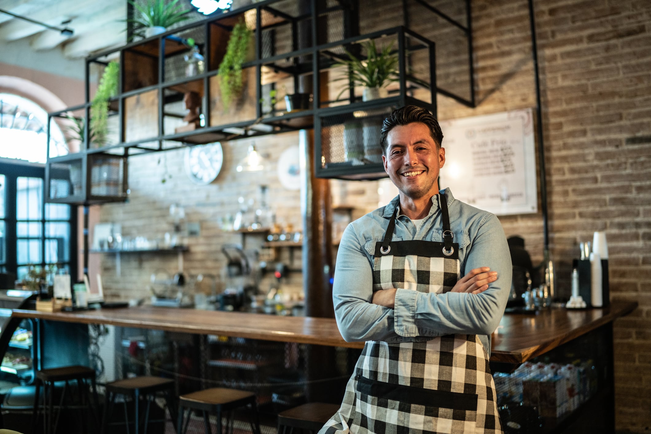 Restaurant owner in an apron standing at the bar of his café